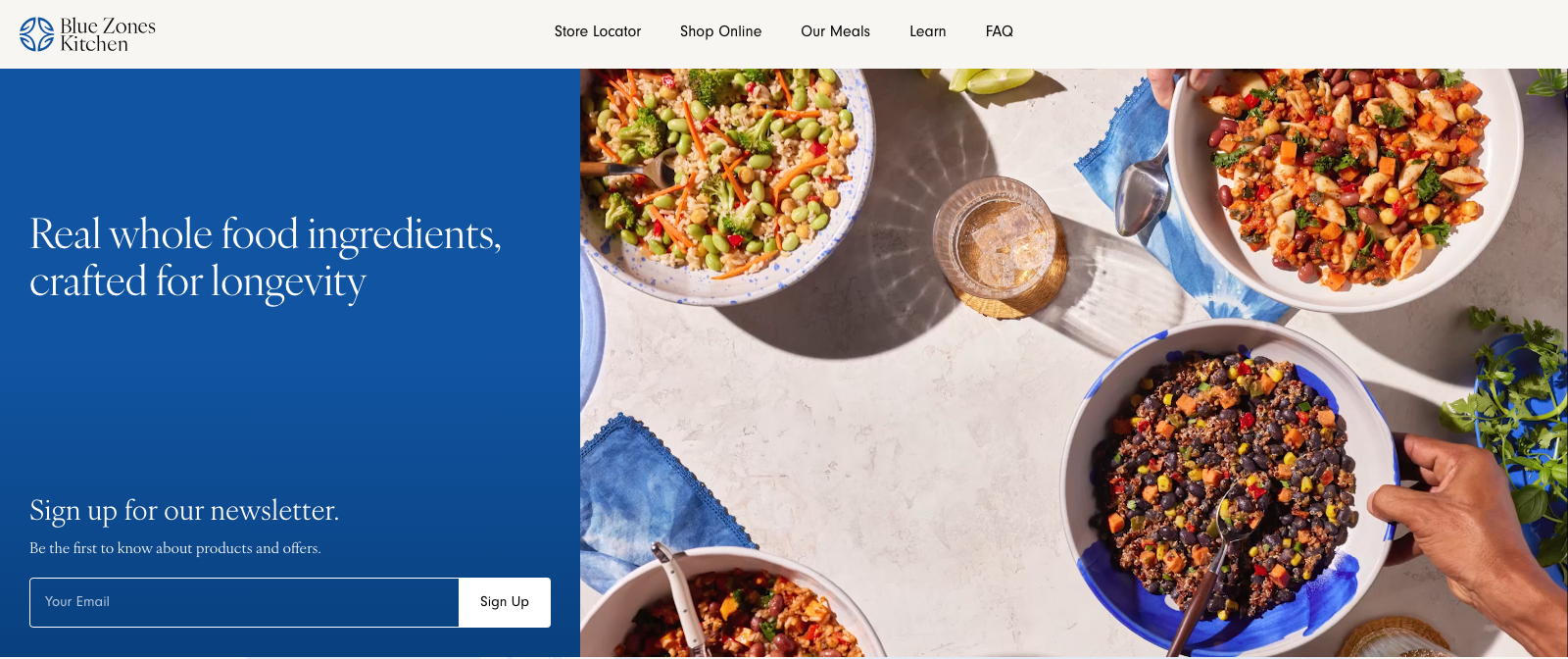 Screenshot of the Blue Zones Kitchen website. A blue panel carries the headline "Real whole food ingredients, crafted for longevity" above a newsletter signup, beside a photograph of four bowls of grain, bean and vegetable dishes.